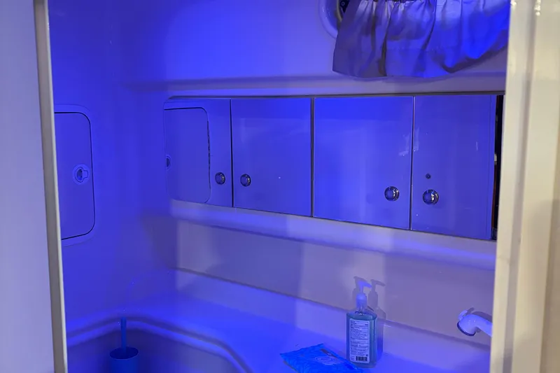 Slide: The Image of Interior of 2004 Sea Ray 320 Sundancer bathroom with blue lighting and storage cabinets. - 29