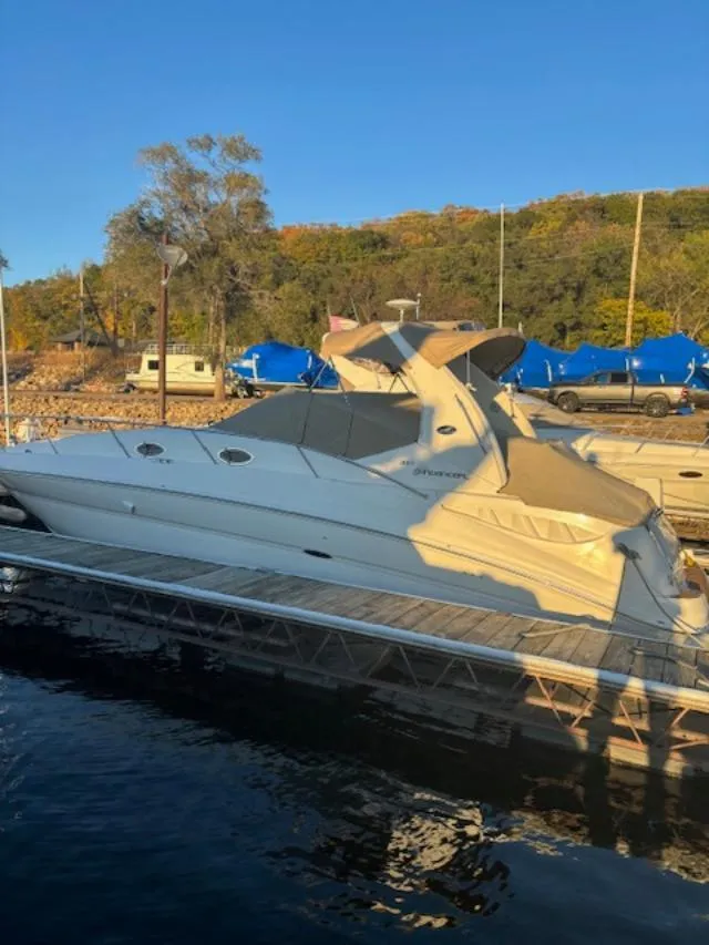 Slide: The Image of 2004 Sea Ray 320 Sundancer docked at a marina, surrounded by scenic autumn foliage. - 6