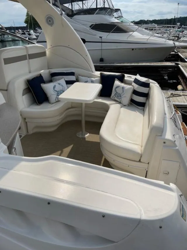 Slide: The Image of 2004 Sea Ray 320 Sundancer boat with cushioned seating and table in a marina setting. - 8