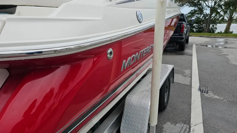 Slide: The Image of 2007 Monterey 214FS Montura boat on trailer, red and white design, parked near water. - 12