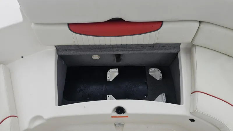 Slide: The Image of Open storage compartment in a 2007 Monterey 214FS Montura boat, featuring white and red upholstery. - 39