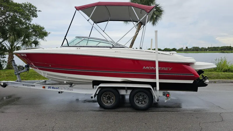 Slide: The Image of 2007 Monterey 214FS Montura boat on trailer by a lake, featuring red and white design. - 49