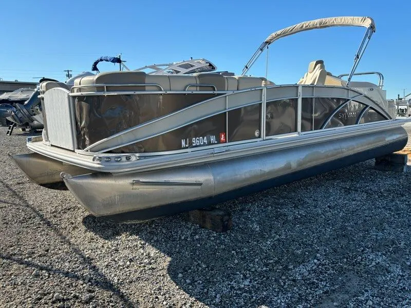 Slide: The Image of 2018 Sylvan S3 pontoon boat on gravel lot, side view, clear sky background. - 1