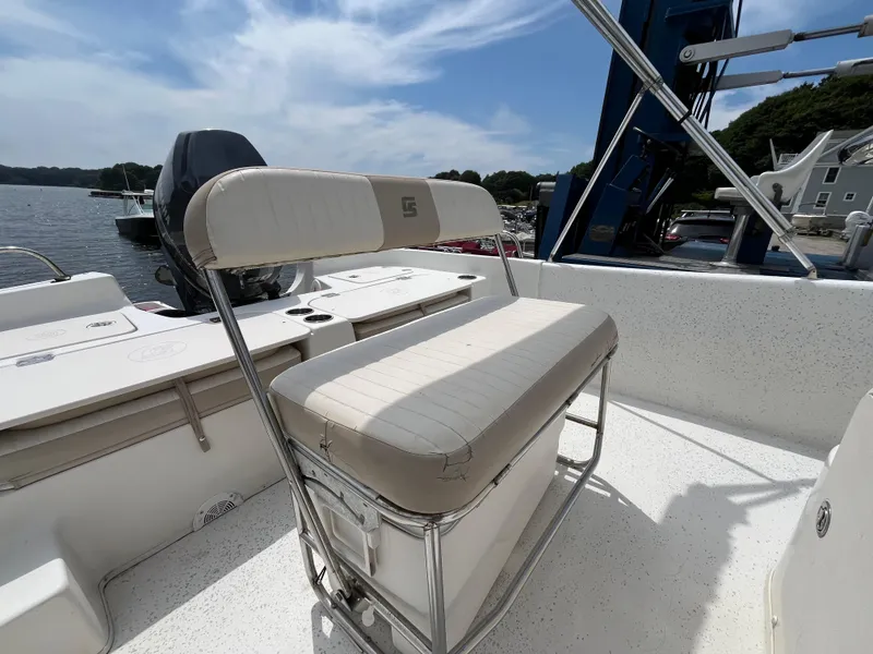 Slide: The Image of 2013 Carolina Skiff 178 DLV boat interior with cushioned seating and storage, docked by the water. - 14
