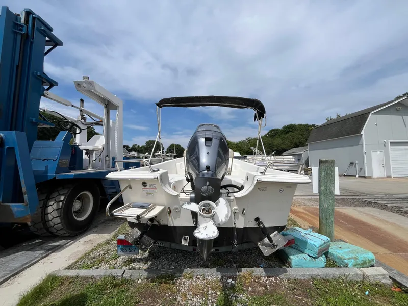 Slide: The Image of 2013 Carolina Skiff 178 DLV boat with outboard motor, parked near a marina. - 5