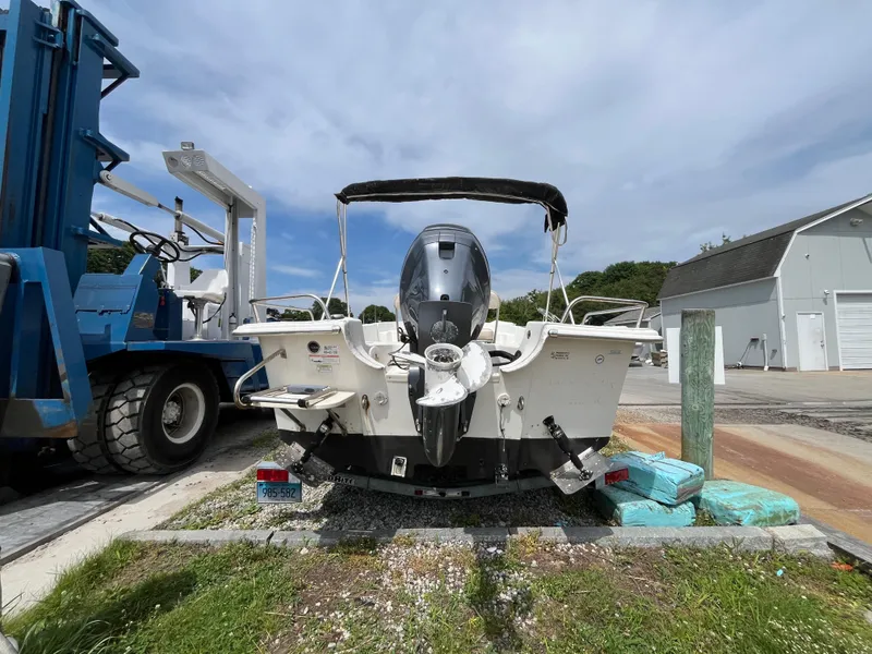 Slide: The Image of 2013 Carolina Skiff 178 DLV boat with outboard motor, parked near a marina. - 6