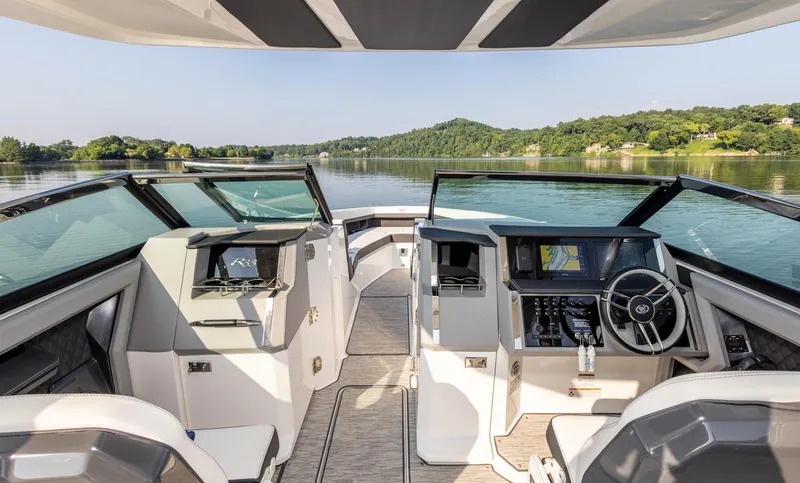 Slide: The Image of Interior of 2023 Cobalt R33 boat with modern dashboard, steering wheel, and scenic lake view. - 23