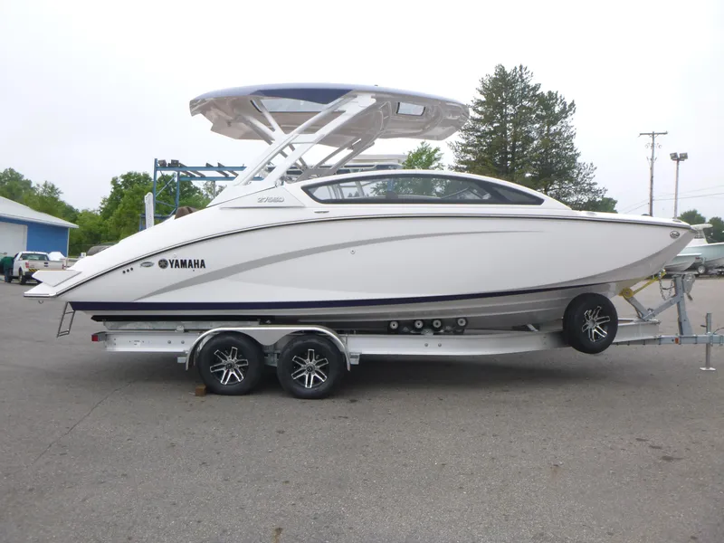 The Image of 2025 Yamaha Boats 275 SD on trailer, sleek white design, parked outdoors. - 1