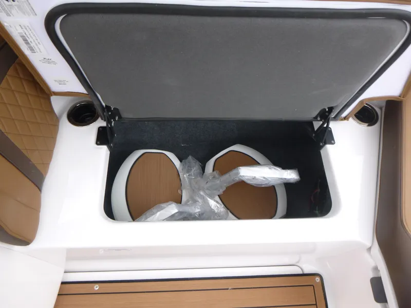Slide: The Image of Open storage compartment in 2025 Yamaha Boats 275 SD, featuring brown and white interior. - 15