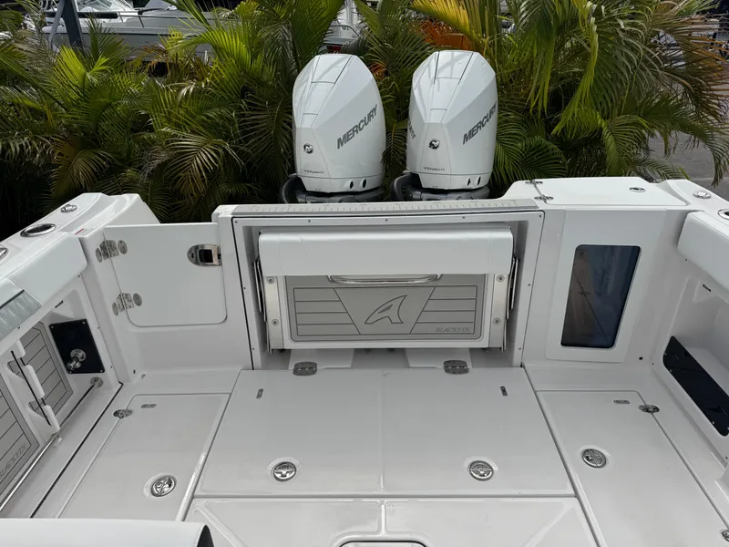 Slide: The Image of 2026 Blackfin 302 DC boat deck with dual Mercury engines, surrounded by lush greenery. - 37