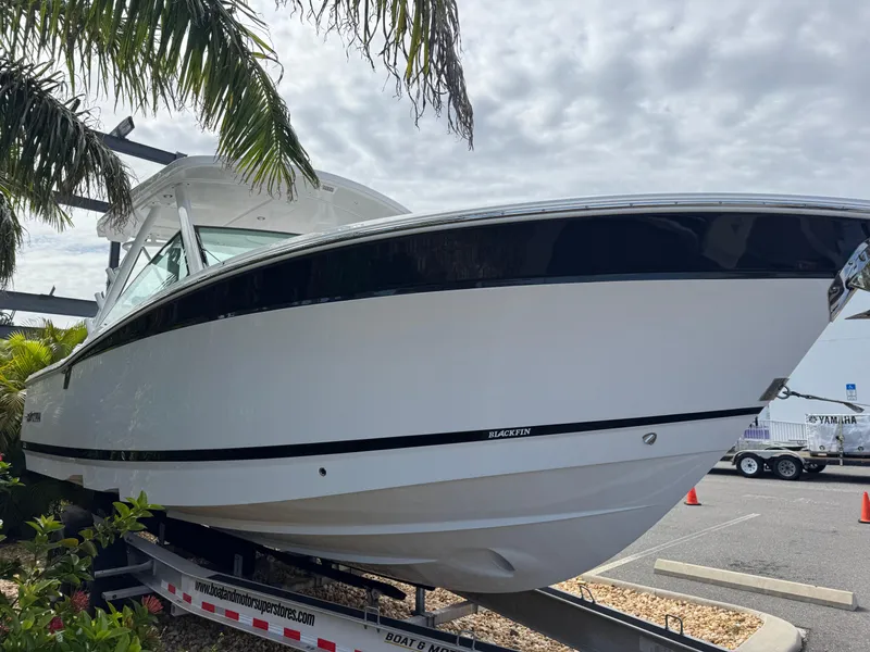 Slide: The Image of 2026 Blackfin 302 DC boat on trailer, surrounded by palm trees and cloudy sky. - 5