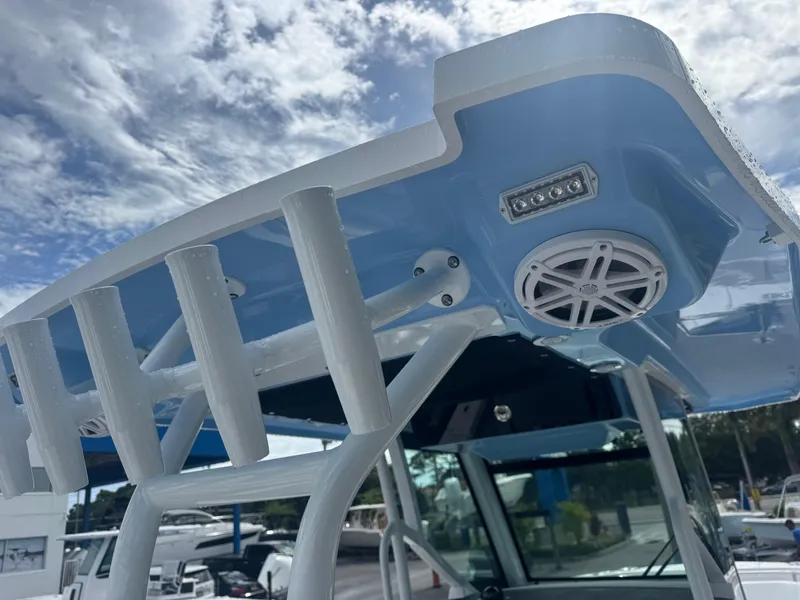Slide: The Image of 2026 Blackfin 302 CC boat T-top with speakers and rod holders under a cloudy sky. - 21