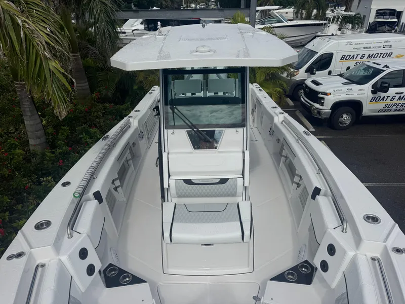 Slide: The Image of 2026 Blackfin 302 CC boat interior with seating and console, surrounded by tropical plants. - 32