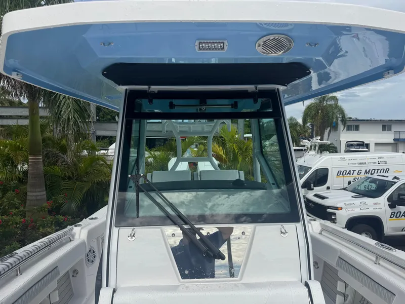 Slide: The Image of 2026 Blackfin 302 CC boat with sleek design, docked near palm trees and service vehicles. - 33