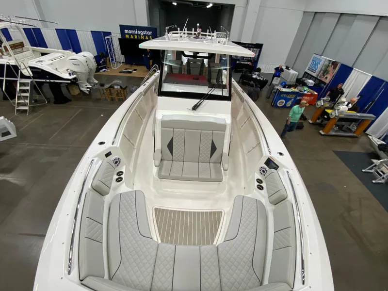 Slide: The Image of 2024 Pursuit S 358 boat interior at a marine exhibition, showcasing spacious seating and modern design. - 14