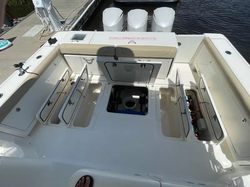 Slide: The Image of 2021 Pursuit OS 385 Offshore boat deck with open storage compartments and triple engines. - 11