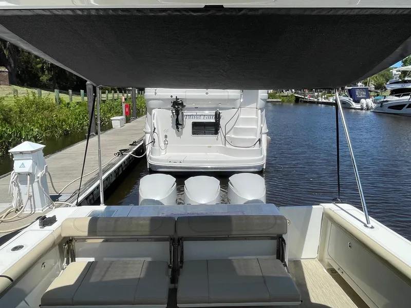 Slide: The Image of 2021 Pursuit OS 385 Offshore boat docked, featuring spacious seating and triple outboard engines. - 13