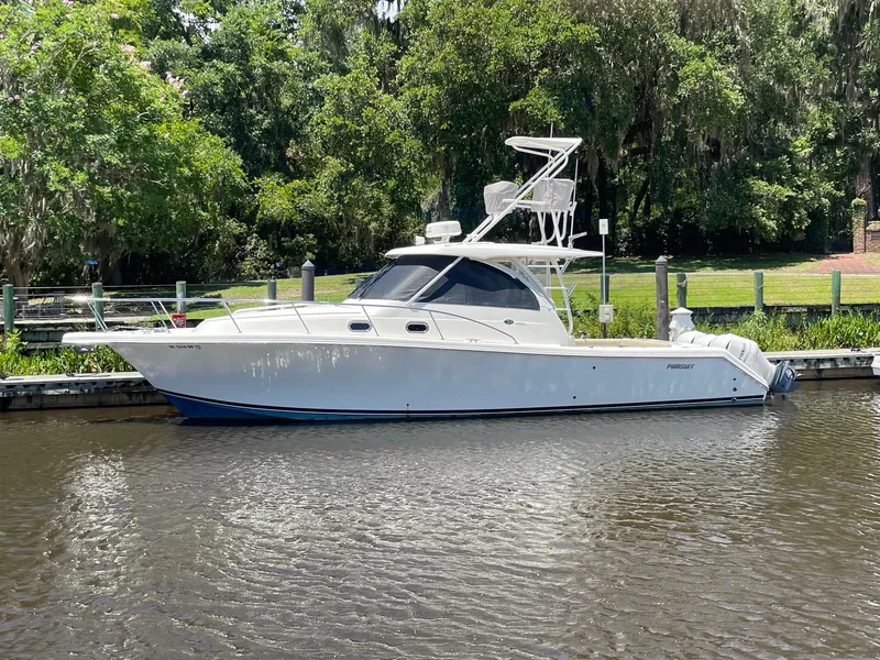 Slide: The Image of 2021 Pursuit OS 385 Offshore boat docked on a calm river with lush greenery. - 3