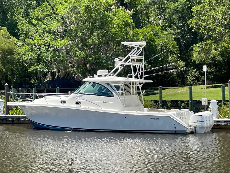Slide: The Image of 2021 Pursuit OS 385 Offshore boat docked by lush greenery. - 4