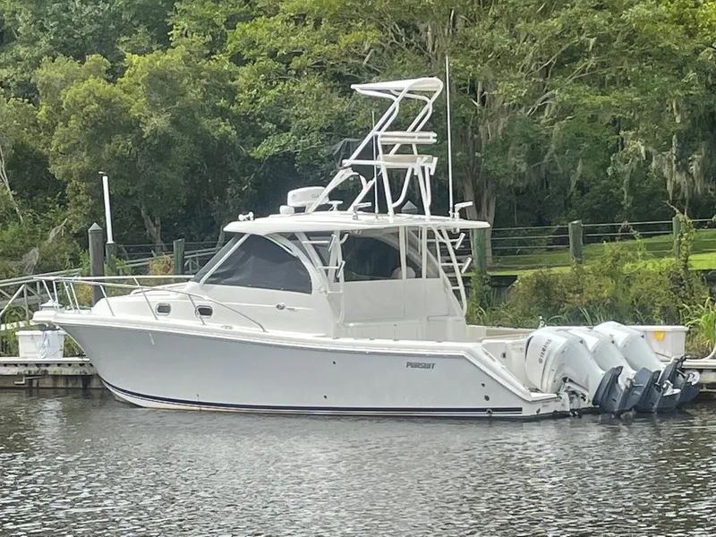Slide: The Image of 2021 Pursuit OS 385 Offshore boat docked by lush greenery. - 5