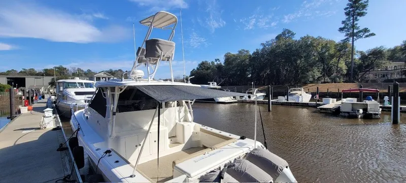 Slide: The Image of 2021 Pursuit OS 385 Offshore boat docked at a marina under a clear blue sky. - 6