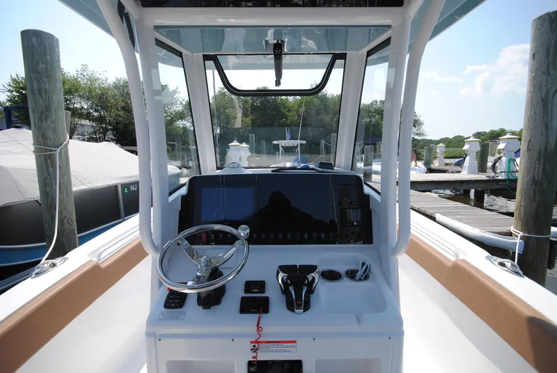 Slide: The Image of 2022 Sea Hunt Ultra 265 SE boat dashboard with steering wheel and controls at dock. - 7
