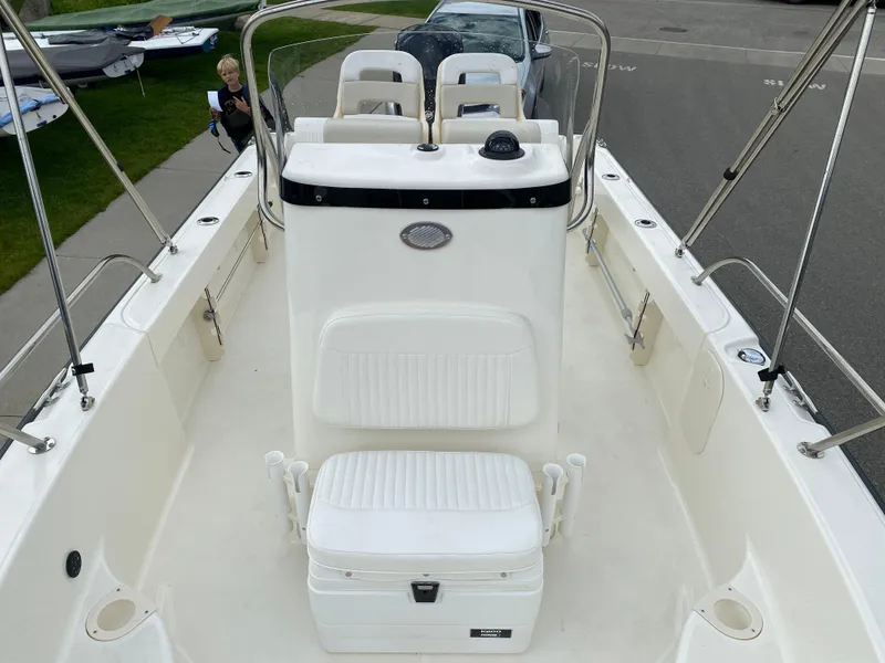 Slide: The Image of 2021 Boston Whaler 190 Outrage boat interior with seating and console, parked on street. - 14