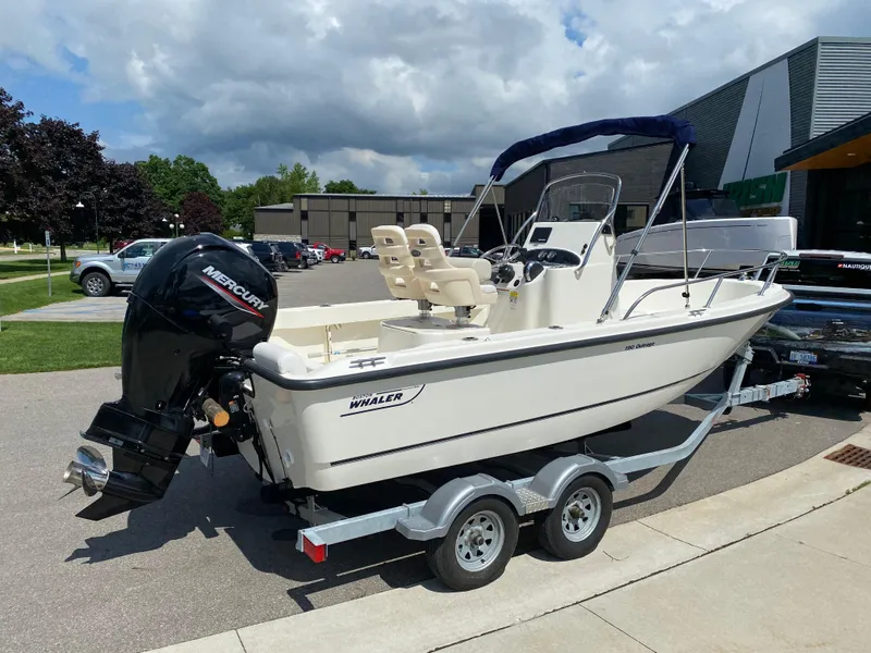 Slide: The Image of 2021 Boston Whaler 190 Outrage boat on trailer, parked outdoors with Mercury engine. - 2