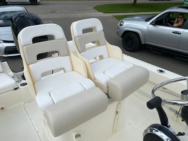 Slide: The Image of 2021 Boston Whaler 190 Outrage boat seats and steering wheel, parked near vehicles. - 24