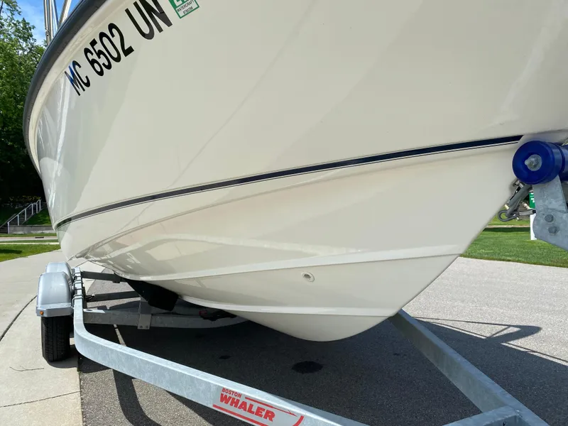 Slide: The Image of 2021 Boston Whaler 190 Outrage boat on trailer, close-up view of hull and registration. - 8