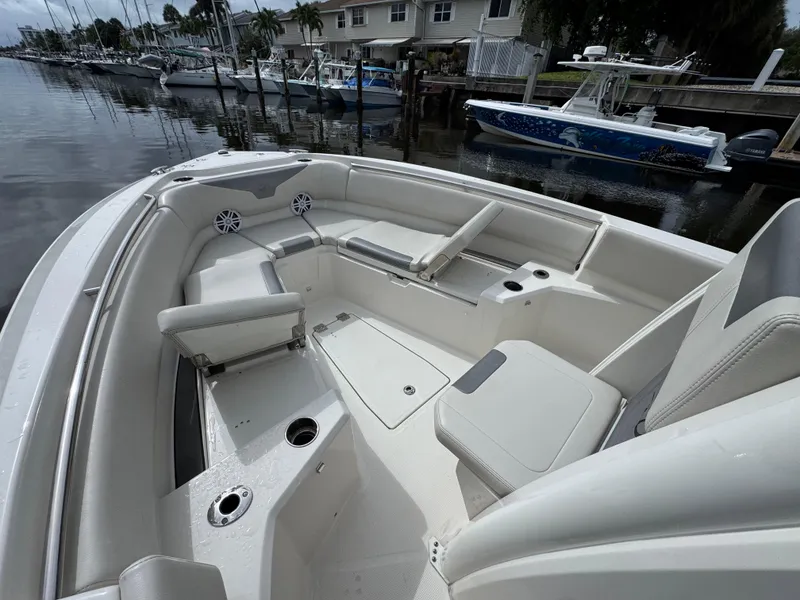Slide: The Image of 2025 Sailfish 232 CC boat interior with spacious seating and cup holders, docked by a calm marina. - 11