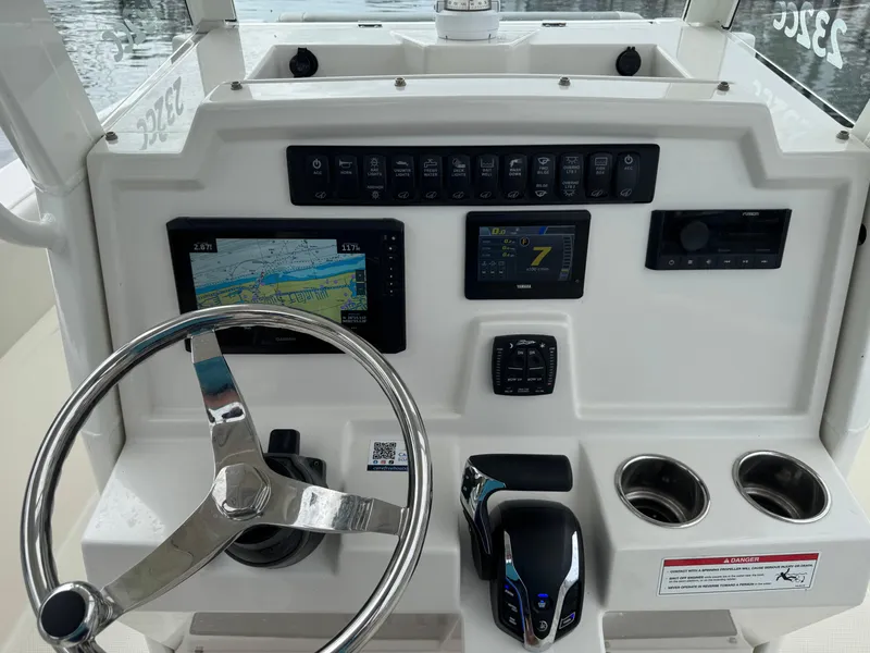 Slide: The Image of 2025 Sailfish 232 CC boat interior with helm seat and steering wheel, docked at marina. - 8