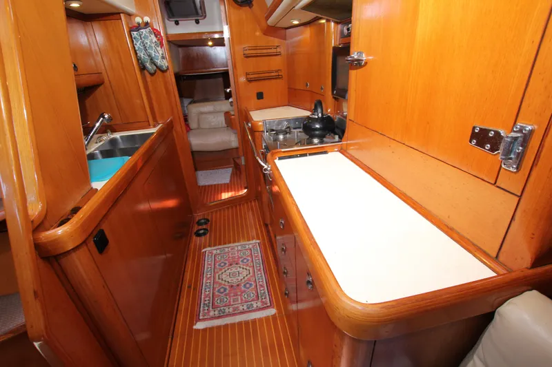 Slide: The Image of Interior of 1997 Nautor Swan 48 yacht, featuring wooden cabinetry and compact kitchen area. - 34