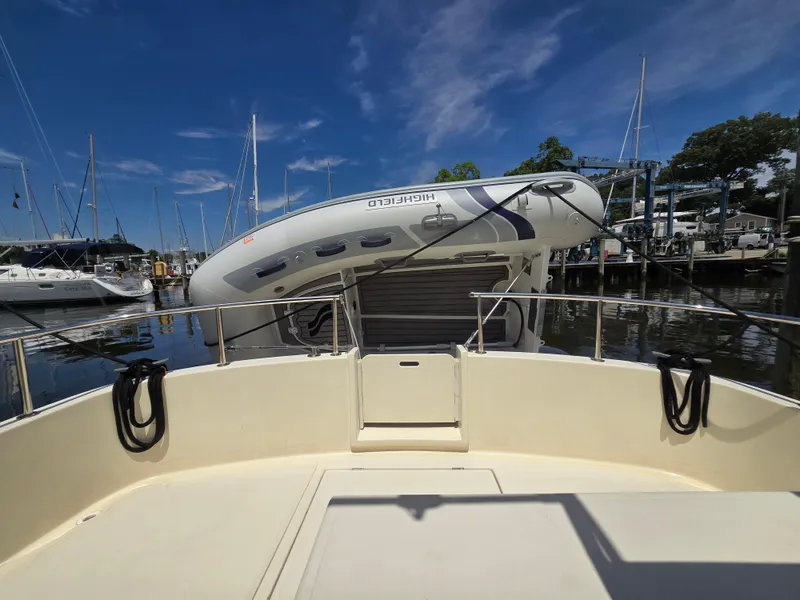 Slide: The Image of 2001 Nordic Tug 32 with inflatable boat on deck, docked at marina under clear blue sky. - 13