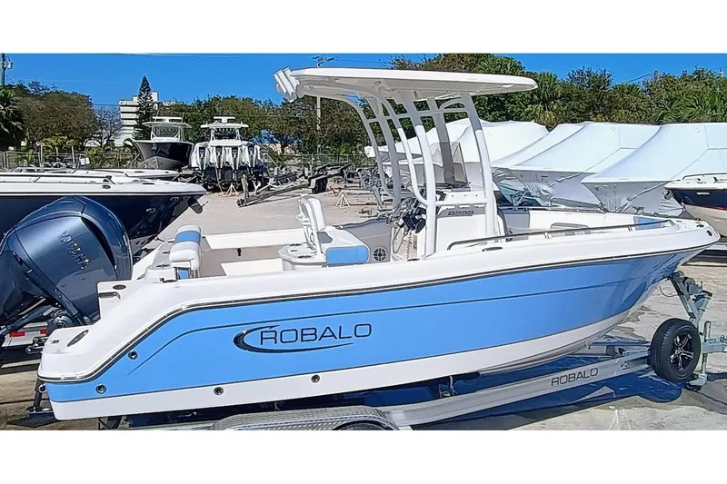 The Image of 2025 Robalo R222 Center Console boat in blue and white on a trailer. - 0