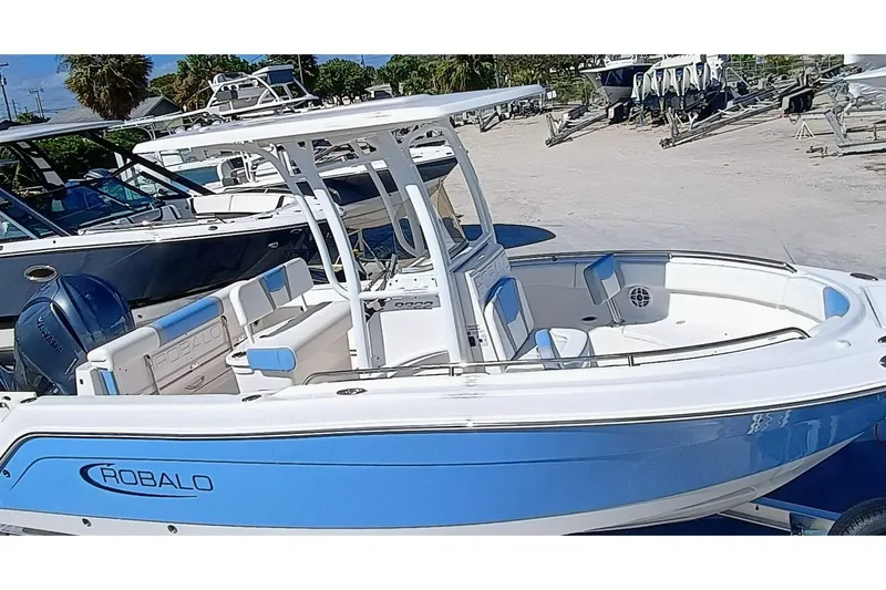 Slide: The Image of 2025 Robalo R222 Center Console boat in blue and white, docked outdoors. - 2