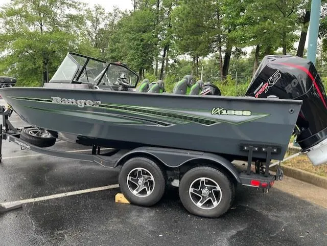 Slide: The Image of 2023 Ranger VX1888 WT boat on trailer, parked outdoors, with trees in background. - 6