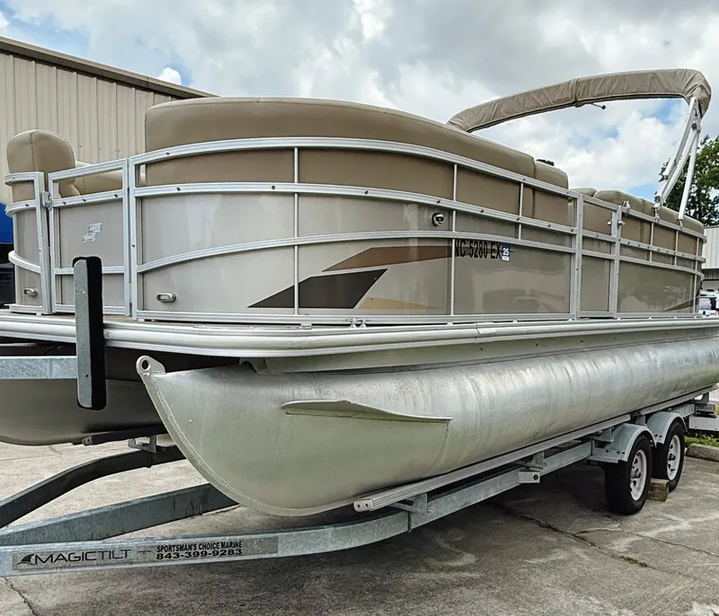 Slide: The Image of 2022 Starcraft LX22 pontoon boat on trailer, beige color, parked outdoors. - 23