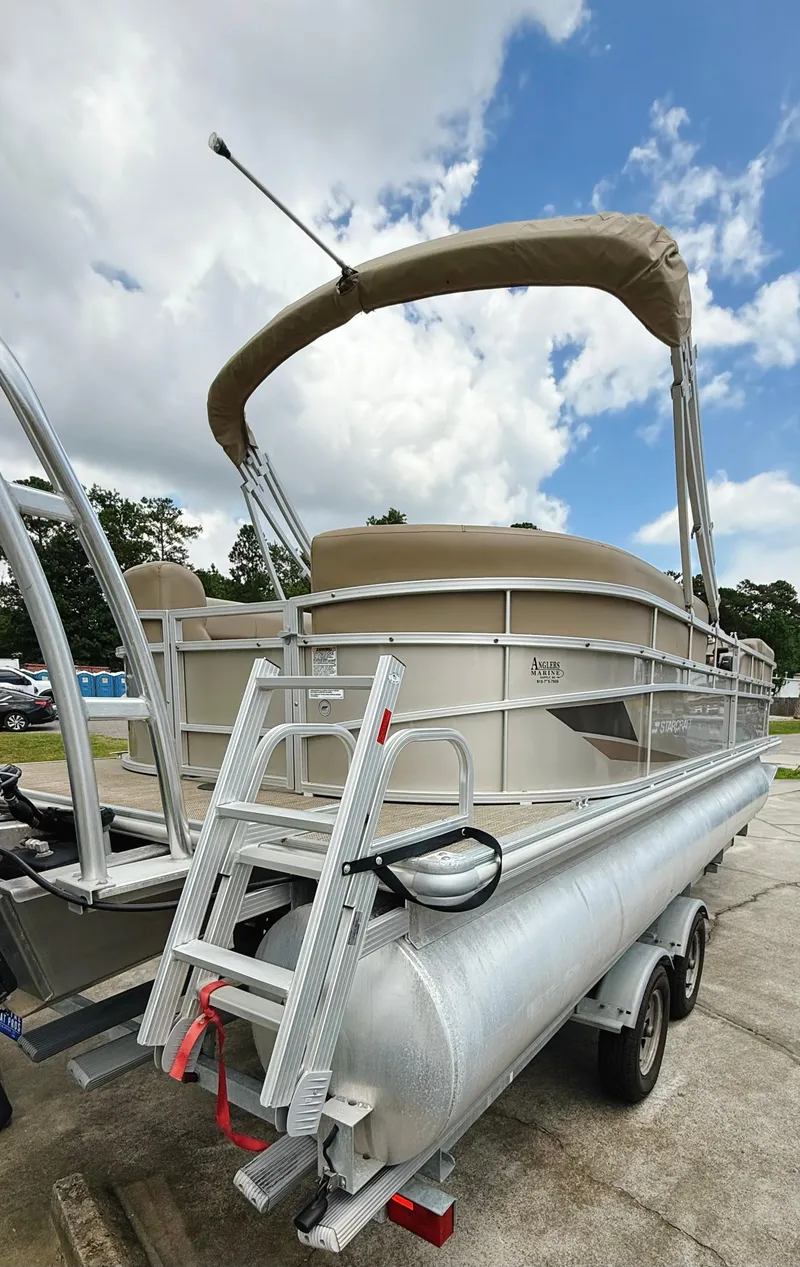 Slide: The Image of 2022 Starcraft LX22 pontoon boat on trailer under cloudy sky. - 24
