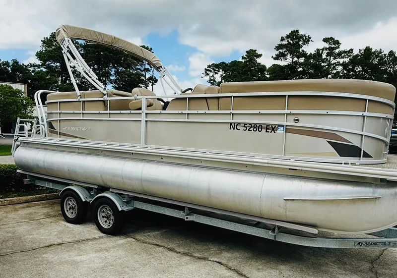 Slide: The Image of 2022 Starcraft LX22 pontoon boat on trailer, parked outdoors under blue sky. - 3