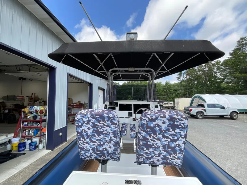 Slide: The Image of 2019 Protector 310 Chase boat with camo seats and canopy, parked near a garage. - 12