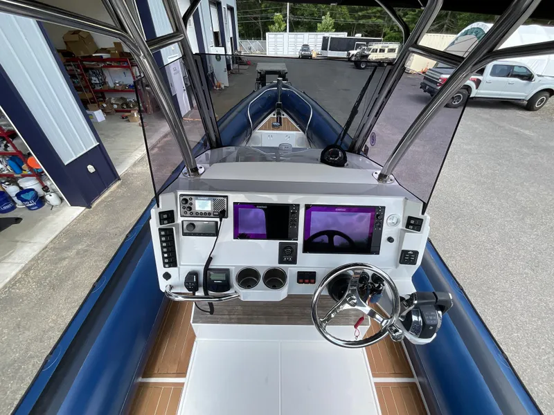 Slide: The Image of 2019 Protector 310 Chase boat dashboard with navigation controls and steering wheel. - 13