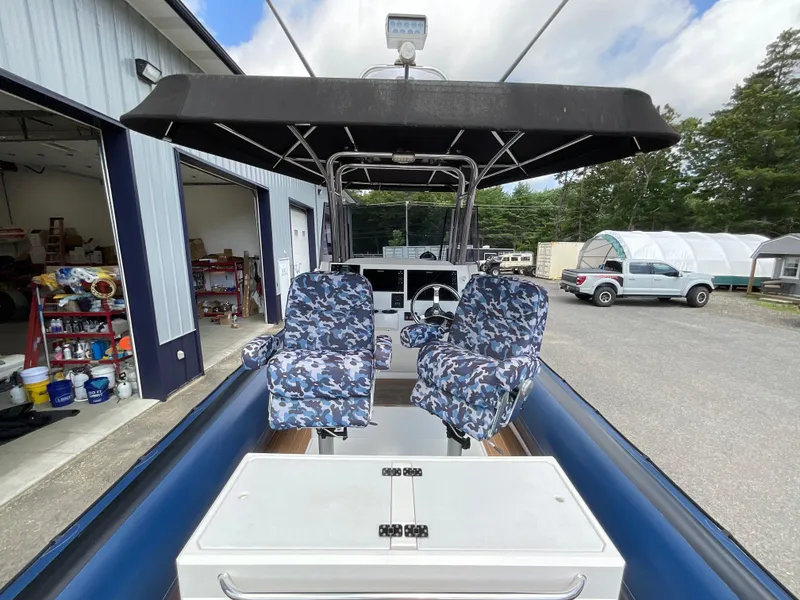 Slide: The Image of 2019 Protector 310 Chase boat with camo seats and canopy, parked near a garage. - 19