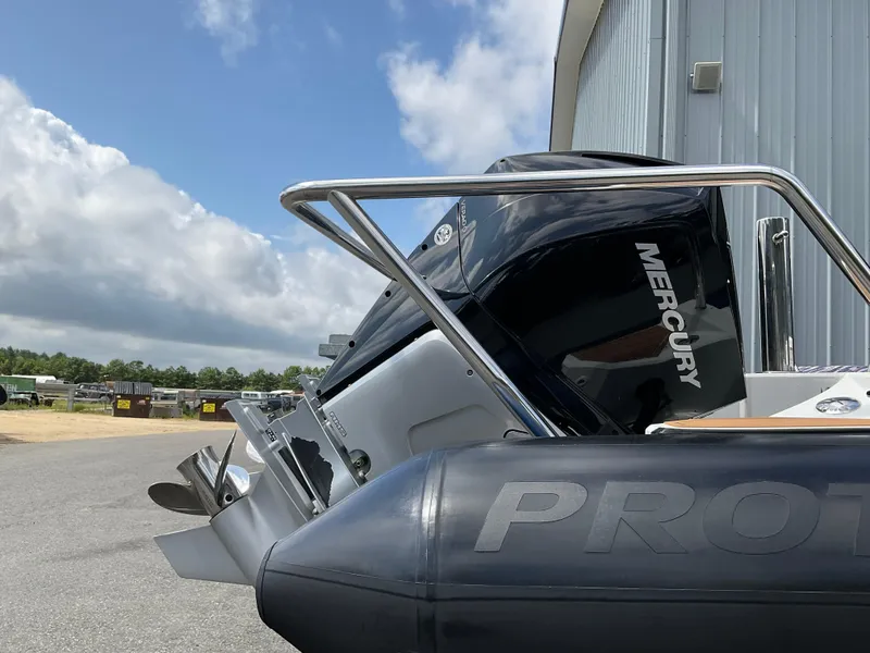 Slide: The Image of 2019 Protector 310 Chase boat with Mercury engine, docked near a metal building under a cloudy sky. - 39