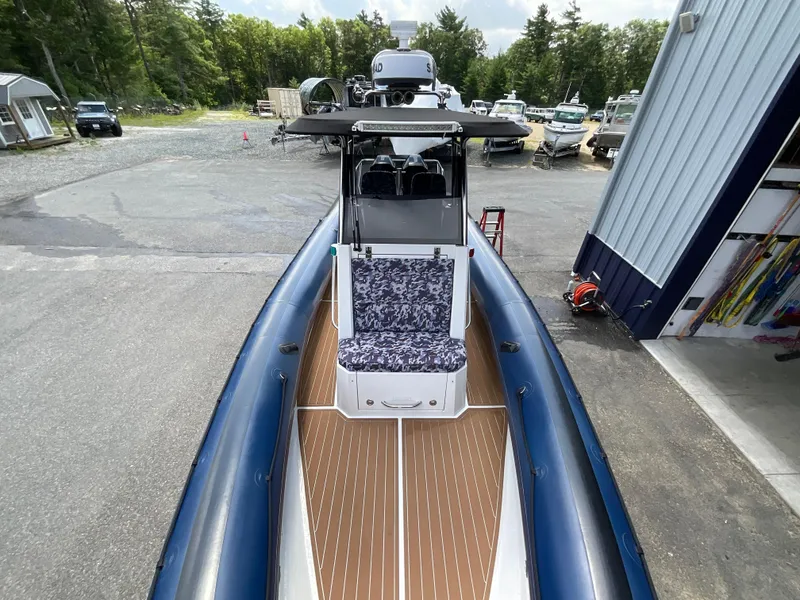 Slide: The Image of 2019 Protector 310 Chase boat with blue inflatable sides and patterned seating, docked outdoors. - 5
