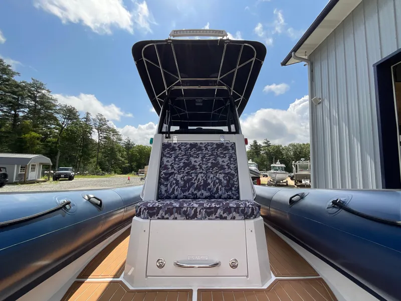 Slide: The Image of 2019 Protector 310 Chase boat with camo seating, docked near a building under a blue sky. - 8