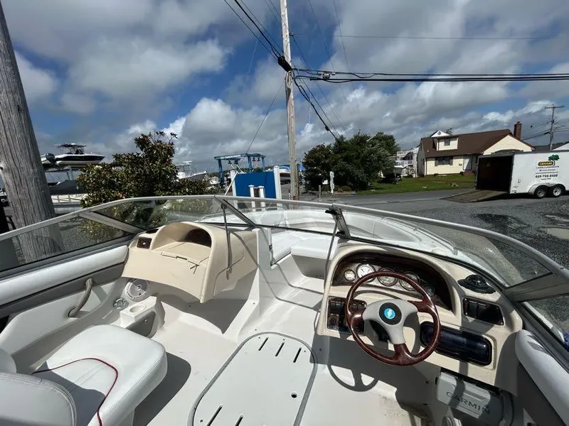 Slide: The Image of 2004 Four Winns 200 Horizon boat interior with steering wheel and dashboard, parked near houses. - 12