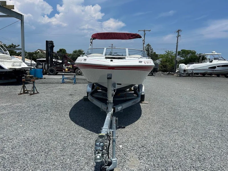 Slide: The Image of 2004 Four Winns 200 Horizon boat on trailer in a gravel lot under blue sky. - 2