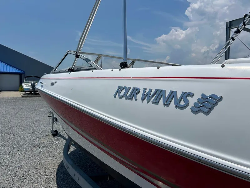 Slide: The Image of 2004 Four Winns 200 Horizon boat with red stripe, parked outdoors under blue sky. - 4
