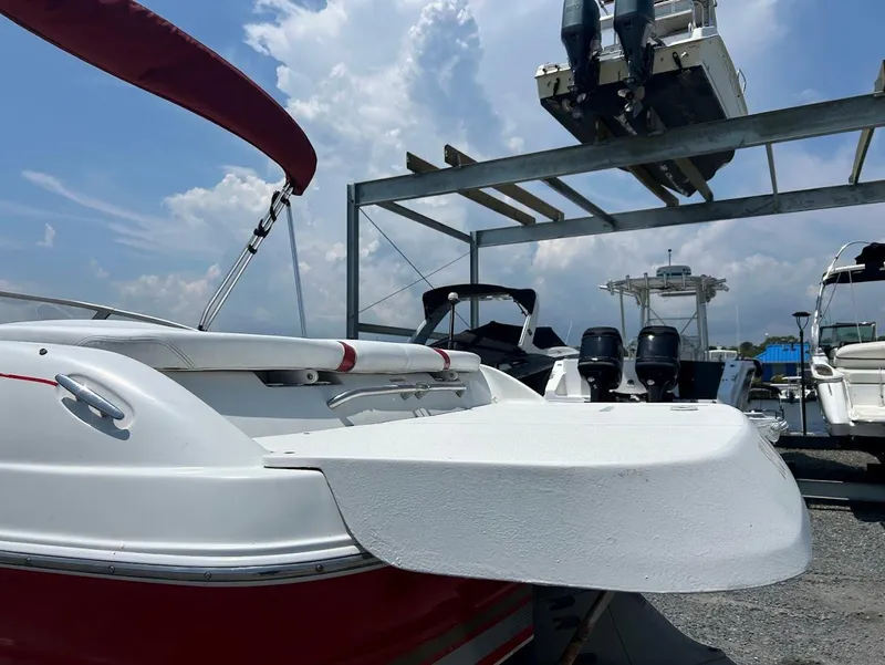 Slide: The Image of 2004 Four Winns 200 Horizon boat with red accents, docked under a cloudy sky. - 5